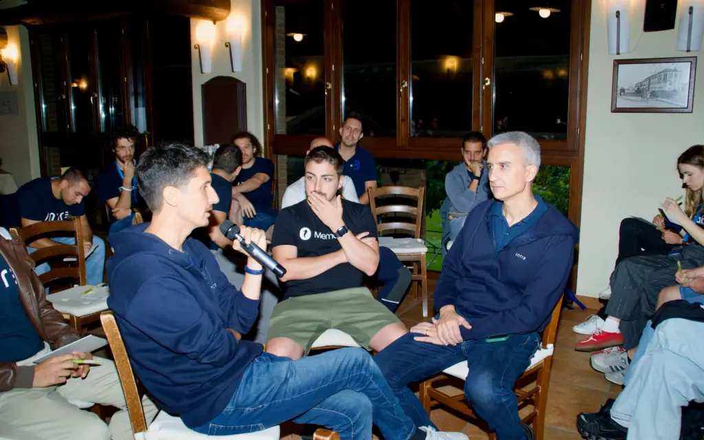 Tre persone intente a discutere sedute durante il fishbowl, e persone sedute intorno. Intré Camp settembre 2025