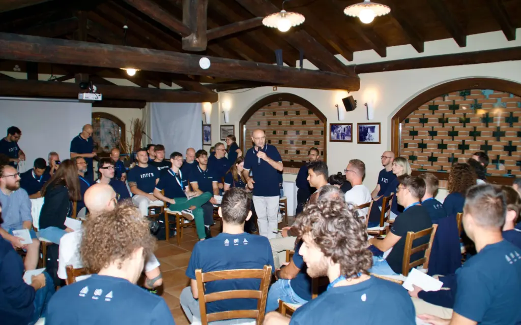 Fabio Ghislandi in piedi presenta il formato fishbowl, e persone sedute intorno. Intré Camp settembre 2025